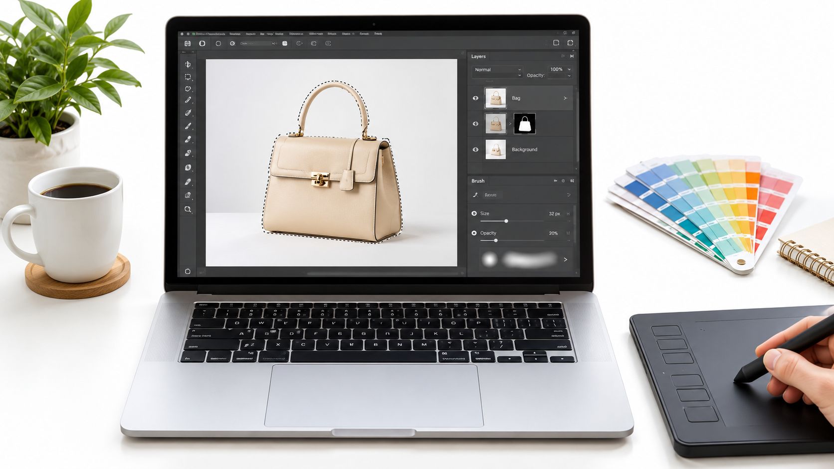 A professional photo editor working on a laptop to change the background color of a designer handbag.