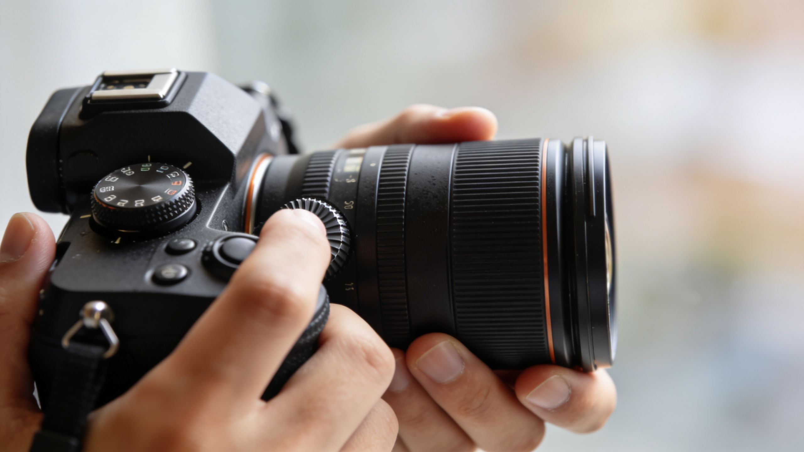 A close-up view of a person's hands adjusting the settings on a professional digital camera lens.