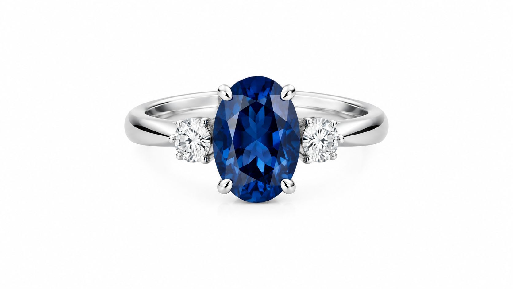A stunning oval blue sapphire engagement ring with side diamond accents set in polished white gold metal.