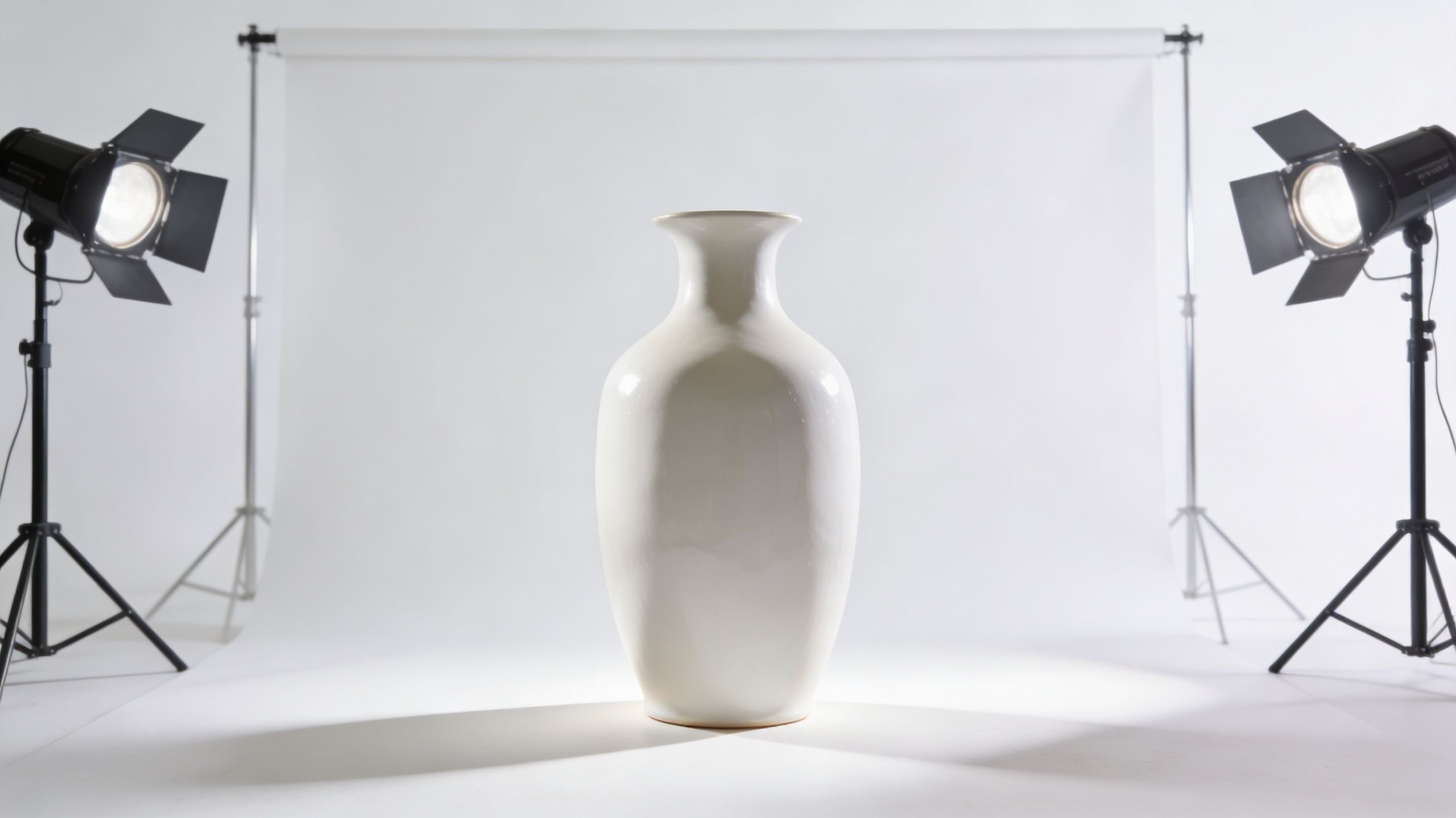A minimalist white ceramic vase centered in a professional photography studio with bright lighting and backdrops.